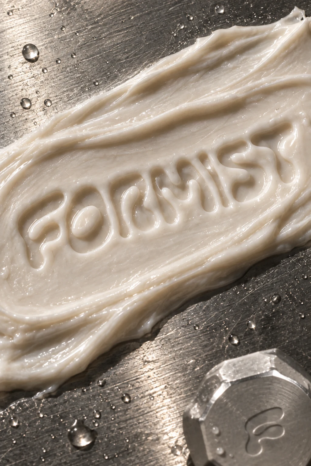FORMIST impression in cream on brushed steel with water and a silver faceted cap
